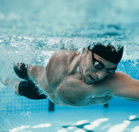 Plavec při kraulu pod vodou v bazénu